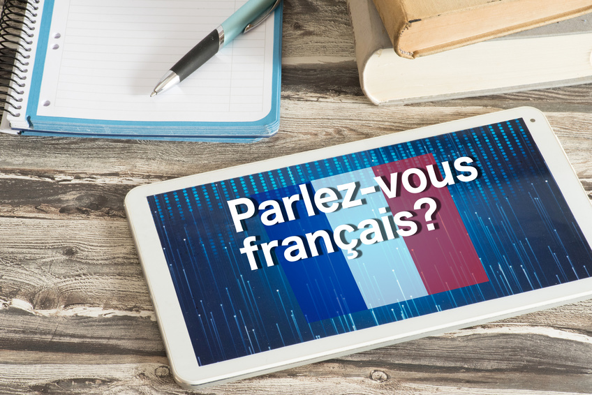 Une tablette posée sur un bureau affiche la question « Parlez-vous français ? ».